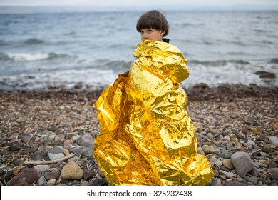 Lesbos, Greece - September 29, 2015: A Refugee Child Uses A Thermal Blanket To Keep Warm