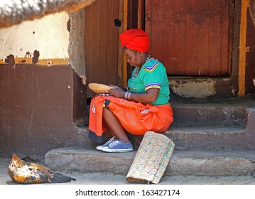 LESEDI CULTURAL VILLAGE, SOUTH AFRICA - JAN 1: African Woman In Traditional Clothes Sitting On The Steps Of House And Work With Beads On January 1, 2008 At The Lesedi Cultural Village, South Africa.  