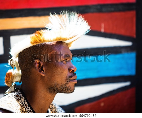 LESEDI CULTURAL VILLAGE, SOUTH AFRICA - NOVEMBER\
4, 2016. Profile portrait of a young male tribal warrior wearing\
traditional headdress. Zulu is one of the oldest remaining tribes\
in South Africa.