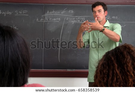 The Lesson College Professor In Front Of A Blackboard Gesturing During His Lecture To The Lesson College Professor In Front Of A Blackboard Gesturing During His Lecture To