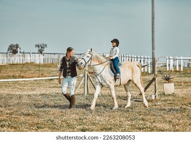 .Lesson, help and woman with a child on a horse for learning, sports and hobby on a farm in Italy. Helping, support and coach teaching a girl horseback riding for a physical activity in countryside. - Powered by Shutterstock