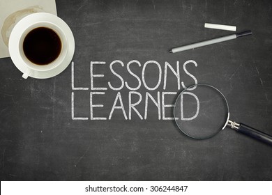 Lessons learned concept on black blackboard with coffee cupt and paper plane