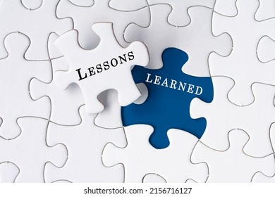 Lessons learned text on Jigsaw Puzzle over dark blue background. - Shutterstock ID 2156716127