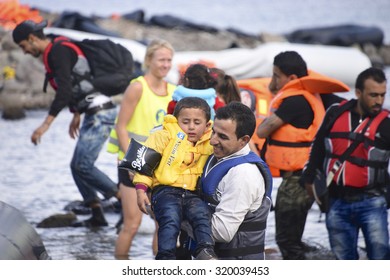 LESVOS, GREECE SEPTEMBER 24, 2015: Refugees arriving in Greece by boat from Turkey.  These Syrian refugees are helped, by Norwegian volunteers, to land their boat near Molyvos, Lesvos (Mytilene).