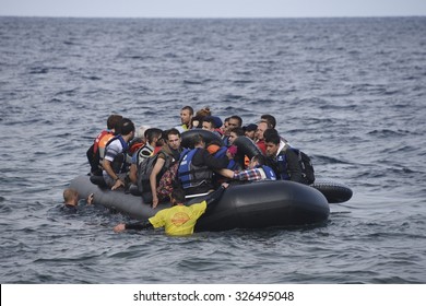LESVOS, GREECE - SEPTEMBER 29, 2015: Refugees arriving in Greece by boat from Turkey. Volunteer lifeguards swam out to assist and guide the boat in when the motor failed.