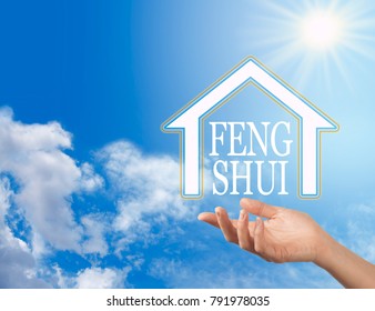 Let the Enlightened Wisdom of Feng Shui into your Home - female hand with a house shape containing the words FENG SHUI floating above against a blue sky background with a bright sun shining down
