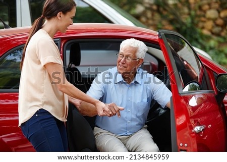 Let me help you out of the car. Shot of a woman helping her senior father out of the car.