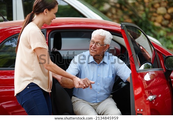 Let me help you out of the car.\
Shot of a woman helping her senior father out of the\
car.