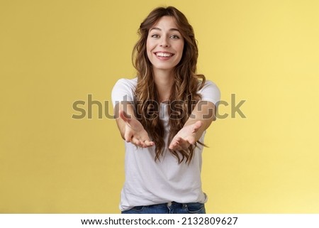 Let me hold it. Sincere tender touched charming curly-haired girl reaching you extend arms smiling lovely tempting grab precious thing receive gift stand yellow background grateful cheerful