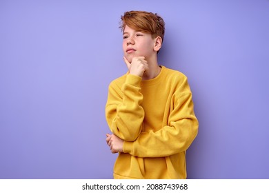 Let me think. Portrait of pensive clever redhead schooler in yellow shirt with puzzled serious expression, child thinking doubting, making choice. indoor studio shot isolated on purple background - Shutterstock ID 2088743968