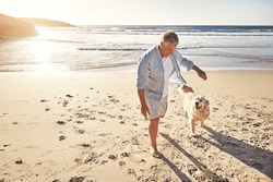 Let Them Off The Leash And Run Free. A Mature Man Taking His Dog For A Walk On The Beach.
