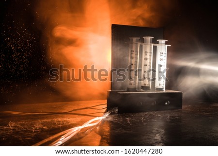 Lethal injection concept. Prisoner handcuffed to death by lethal injection. Creative artwork decoration with scale model on dark with lights.