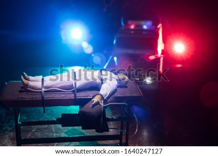 Lethal injection concept. Prisoner handcuffed to death by lethal injection. Creative artwork decoration with scale model on dark with lights.