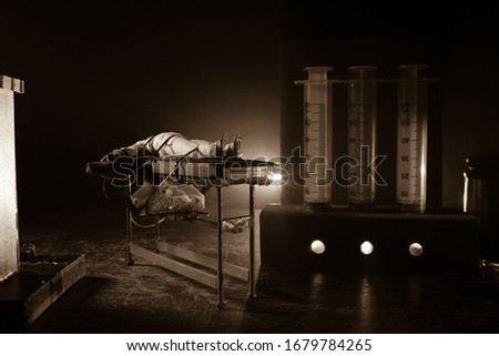 Lethal injection concept. Prisoner handcuffed to death by lethal injection. Creative artwork decoration with scale model on dark with lights.