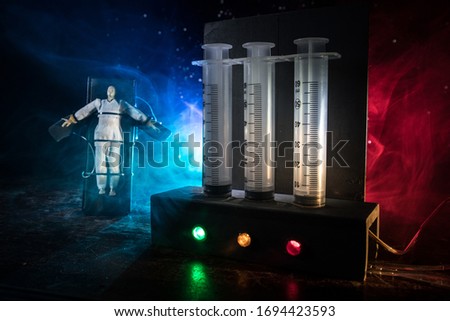 Lethal injection concept. Prisoner handcuffed to death by lethal injection. Creative artwork decoration with scale model on dark with lights.