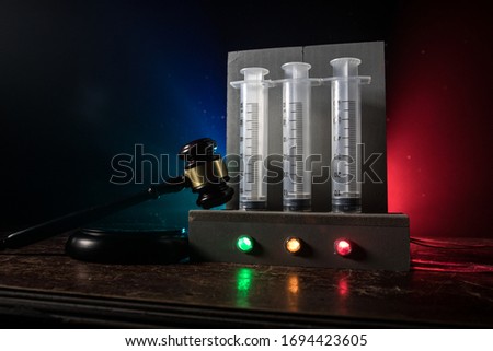 Lethal injection concept. Prisoner handcuffed to death by lethal injection. Creative artwork decoration with scale model on dark with lights.
