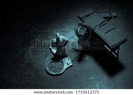 Lethal injection concept. Prisoner handcuffed to death by lethal injection. Creative artwork decoration with scale model on dark with lights.