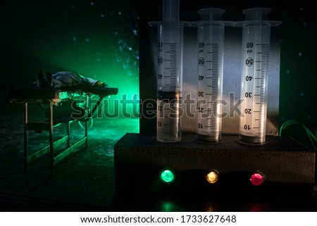 Lethal injection concept. Prisoner handcuffed to death by lethal injection. Creative artwork decoration with scale model on dark with lights.