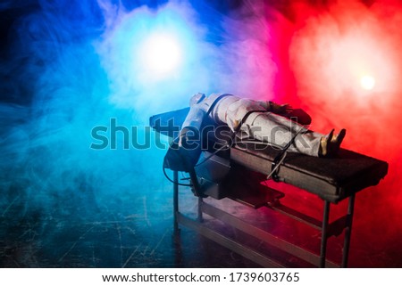 Lethal injection concept. Prisoner handcuffed to death by lethal injection. Creative artwork decoration with scale model on dark with lights.