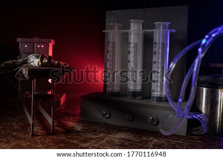 Lethal injection concept. Prisoner handcuffed to death by lethal injection. Creative artwork decoration with scale model on dark with lights.