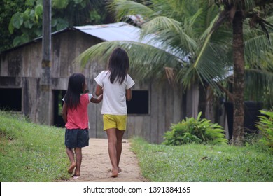 Leticia, Colombia - February, 2019: The People In The Amazon, Two Sisters Are Walking In An Indigenous Village In The Colombian Amazon. 