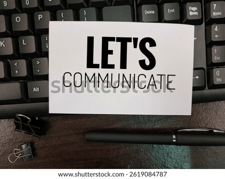 Let's Communicate text on white paper placed on computer keyboard with black pen, concept of online communication, business conversation, writing and digital interaction. 