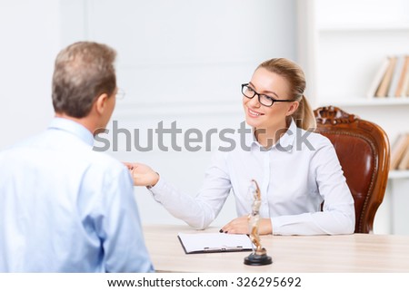 Lets discuss it. Nice agreeable delighted lawyers sitting at the table and having conversation while being busy at  work