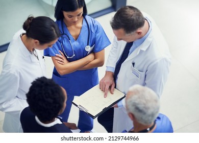 Lets up the dosage for this patient. Shot of a group of doctors talking together over a medical chart while standing in a hospital. - Powered by Shutterstock