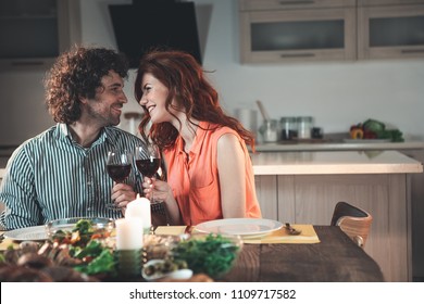 Lets drink for us. Pleased married couple is having dinner by candlelight. They are drinking wine and smiling. Lovers are looking at each other with fondness. Copy space 