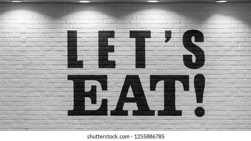 Let's EAT! fast food store logo display on white brick wall with the light from ceiling.