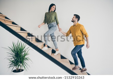 Let's explore this place! Full size profile photo of handsome guy and his pretty lady walking to bedroom go up stairs in just bought modern flat indoors wear casual clothes