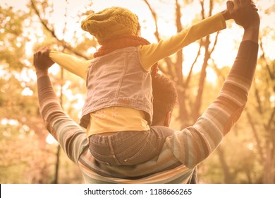 Let's Fly!  Young African American Father Carrying His Daughter On Shoulders. From Back. Close Up.