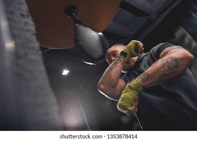 Let's get ready to rumble. Arm workout, professional young boxer with green hands wraps hitting punching speed bag in boxing gym - Powered by Shutterstock