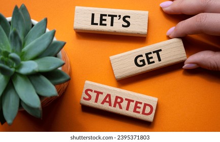 Lets get started symbol. Concept words Lets get started on wooden blocks. Beautiful orange background. Businessman hand. Business and Lets get started concept. Copy space. - Shutterstock ID 2395371803