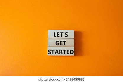 Lets get started symbol. Concept words Lets get started on wooden blocks. Beautiful orange background. Business and Lets get started concept. Copy space.