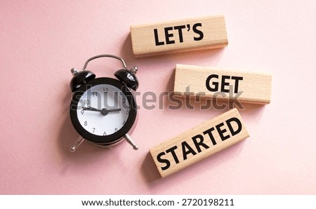 Lets get started symbol. Concept words Lets get started on wooden blocks. Beautiful pink background with alarm clock. Business and Lets get started concept. Copy space.