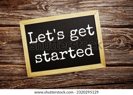 Let's get started  write on blackboard top view on wooden background