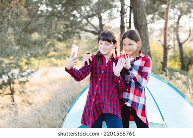 Lets Go Camping. Family Camping. Reach Destination Place. Cheerful Teenage Girls Talking On A Video Call, Looking At The Phone Screen In The Middle Of A Pine Forest Near Tent. Hiking Outdoor Adventure