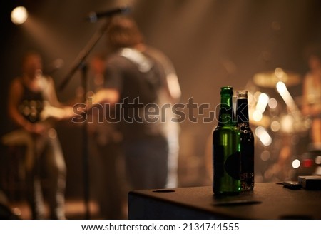 Lets have another. Two beer bottles on a table as a band plays in the background.
