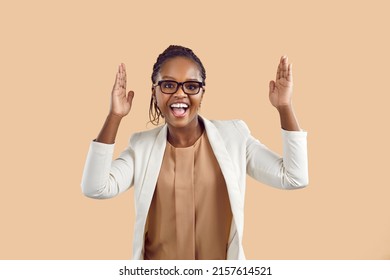 Let's party. Happy african american woman in spectacles and formal suit dancing isolated on solid beige colour background. Excited business lady or corporate company employee having fun after deal