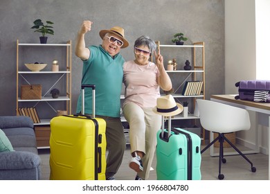 Let's Rock This Summer. Active Senior Couple Having Fun At Home Before Going On Holiday Trip. Portrait Of Happy Aged Husband And Wife With Packed Travel Suitcases Ready For Cool Vacation Together