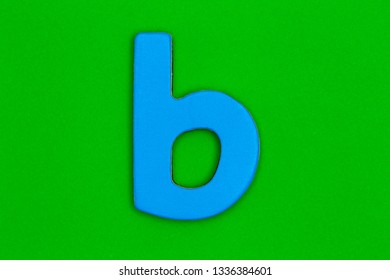 Letter b made of wood painted bright blue on a bright green background - Shutterstock ID 1336384601