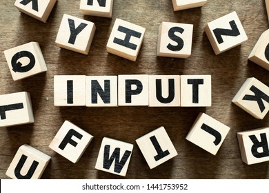 Letter block in word input with another block on wood background