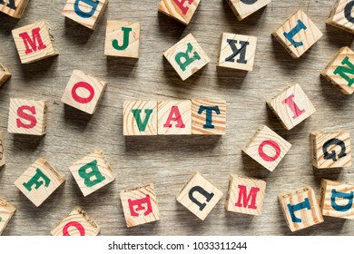 Letter block in word VAT (Abberviation of Value added tax) with another on wood background