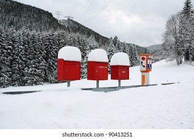 Letter boxes are covered with snow beside an SOS phone device in a remote mountain village - Powered by Shutterstock