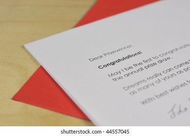 Letter Of Congratulations And Red Envelope On Wooden Desk