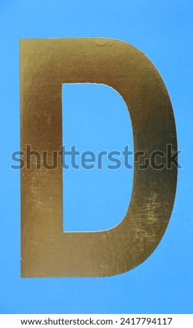 Letter D uppercase - golden color font on blue background, Close up