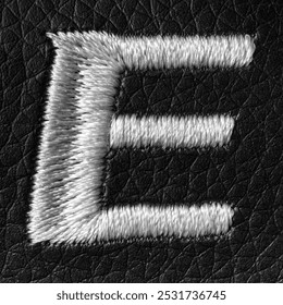 Letter E embroidered with white threads on black leather background. English alphabet. Element for design.