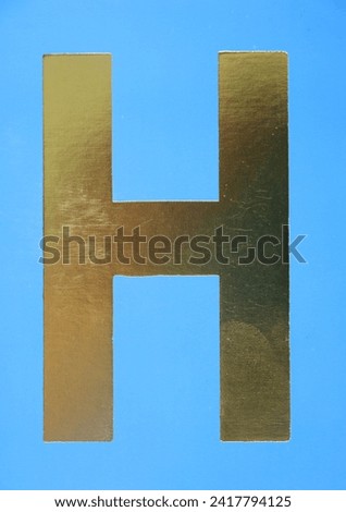Letter H uppercase - golden color font on blue background, Close up