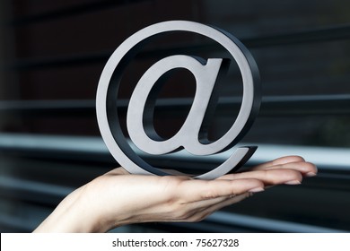 At letter held in hand in front of window symbolizing emailing or the internet.